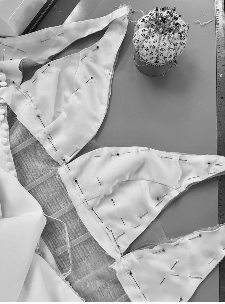 Wedding dress bodice laid flat during alterations, with additional ivory lining pinned into place to reduce sheerness and add coverage.