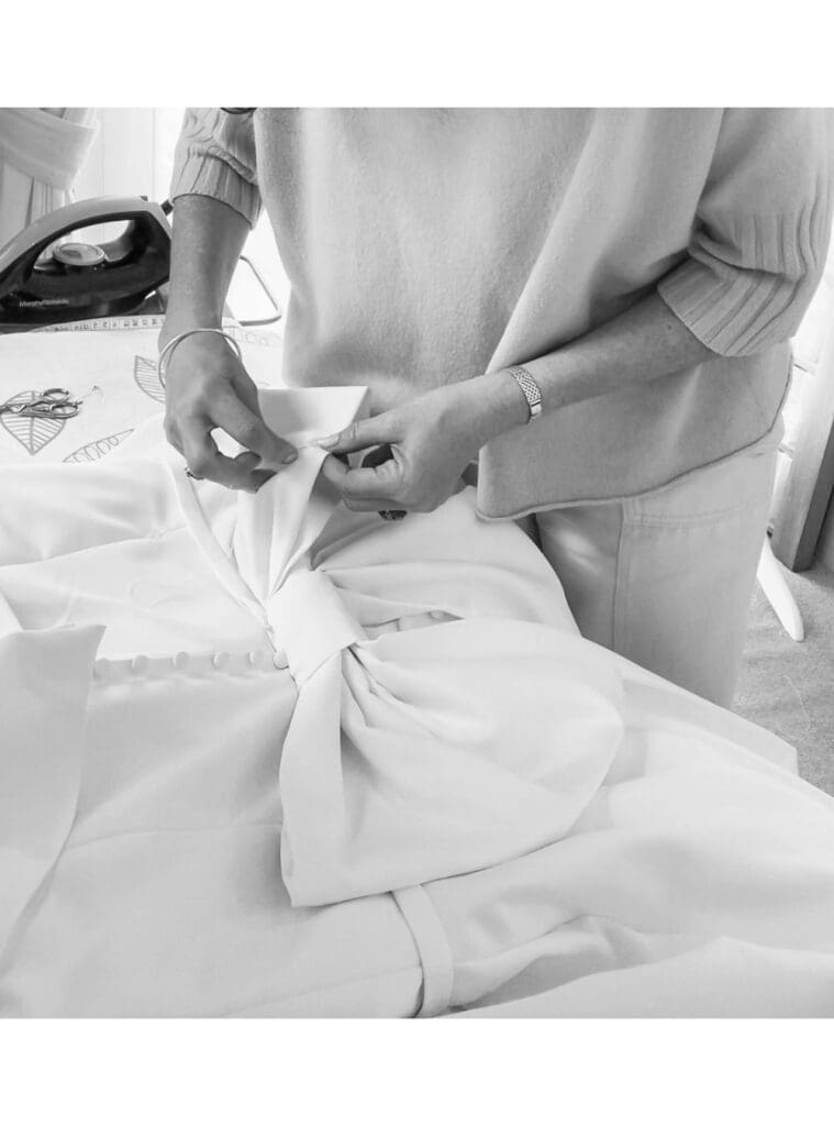 Bespoke satin bowbeing shaped and constructed from the same fabric as the wedding dress before being sewn onto the back.